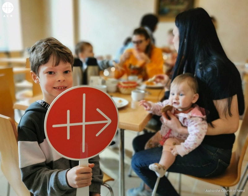 Ucrania niño refugiado comiendo con logo