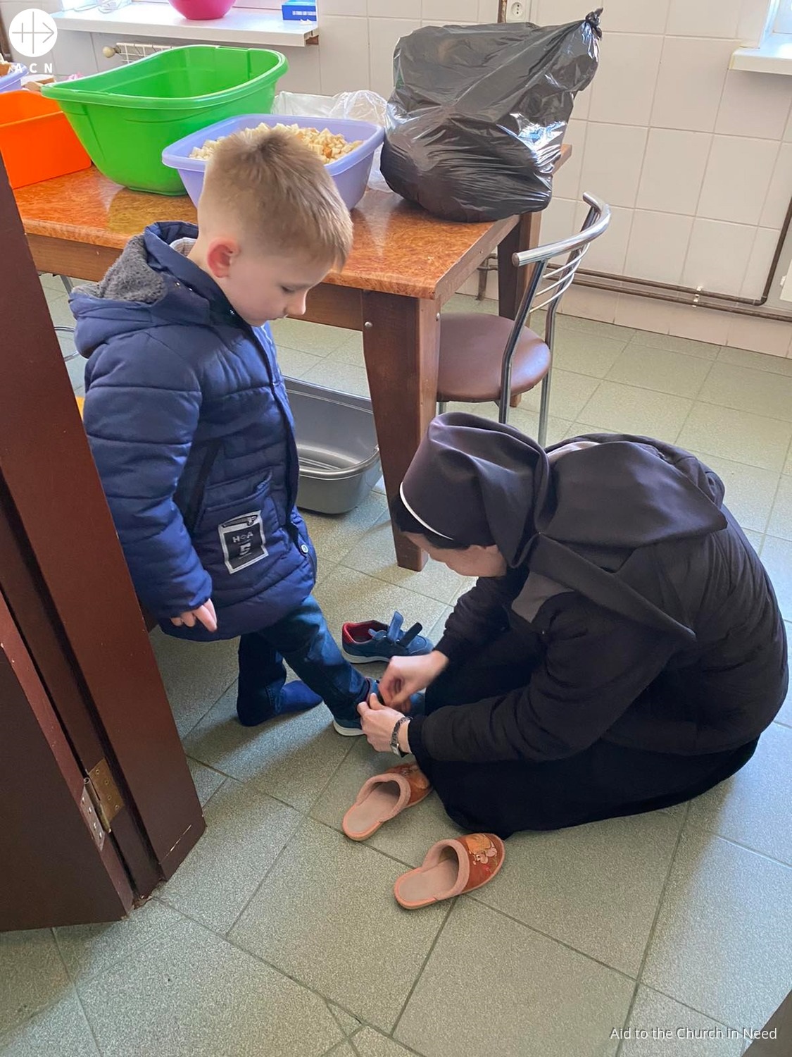 Ucrania proyecto enero 2023 religiosa abrocha zapatos a niño